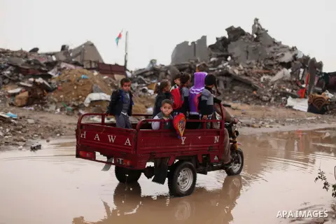 Palestinian school children ride a motorcycle rickshaw past the ruins of houses that witnesses said were destroyed by Israeli shelling during the most recent conflict between Israel and Hamas, on a rainy day in the east...