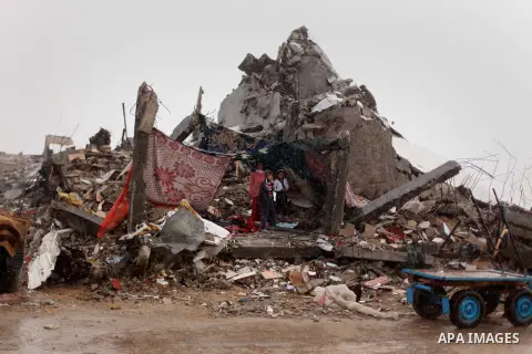 Palestinian children take cover from the rain as they stand atop the ruins of a house, which witnesses said was destroyed by Israeli shelling during the most recent conflict between Israel and Hamas, on a rainy day in th...