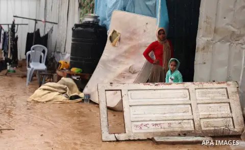 Palestinians who live in a containers as a temporary replacement for their house that witnesses said was destroyed by Israeli shelling during the most recent conflict between Israel and Hamas, take cover from heavy rains...