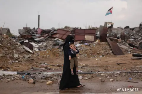 A Palestinian woman carries her son as she walks past a house, which witnesses said was destroyed by Israeli shelling during the most recent conflict between Israel and Hamas, following heavy rain in the east of Khan You...
