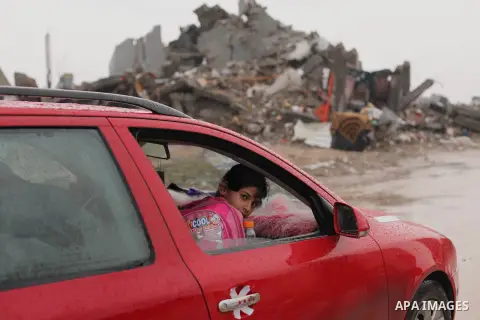 A Palestinian schoolgirl looks out from a car window as it passes by the ruins of a house that witnesses said was destroyed by Israeli shelling during the most recent conflict between Israel and Hamas, on a rainy day in...