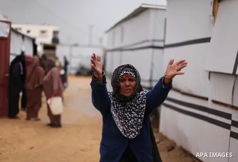 A Palestinian woman who lives in a container as a temporary replacement for her house that witnesses said was destroyed by Israeli shelling during the most recent conflict between Israel and Hamas, speaks as she stands b...