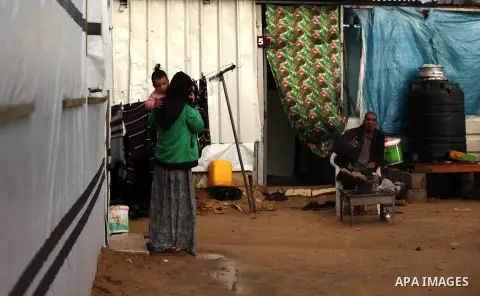 A Palestinian woman who lives in a container as a temporary replacement for her house that witnesses said was destroyed by Israeli shelling during the most recent conflict between Israel and Hamas, walks outside her cont...