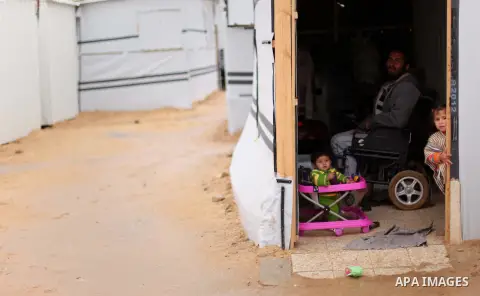 Palestinians who live in a containers as a temporary replacement for their house that witnesses said was destroyed by Israeli shelling during the most recent conflict between Israel and Hamas, take cover from heavy rains...