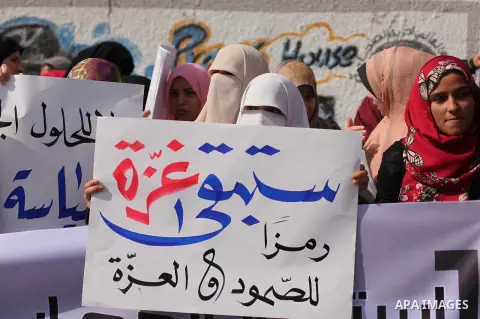 Palestinian supporters of Hamas movement hold banners during a protest organized by the owners of houses which were destroyed by Israeli shelling during the most recent conflict between Israel and Hamas, calling for reco...