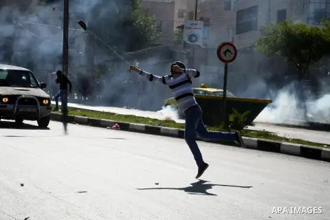 A Palestinian uses a sling shot to throw a stone at Israeli army soldiers during clashes following a protest against the recent visits by Jewish activists to al-Aqsa mosque, in the West Bank city of Hebron November 7, 20...