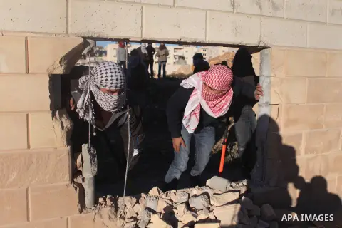 Palestinian youths are seen through a hole knocked in part of Israel's controversial separation barrier, at Bir Nabala village near the West Bank city of Ramallah, on Nov. 08, 2014. In recent weeks there have been near-d...