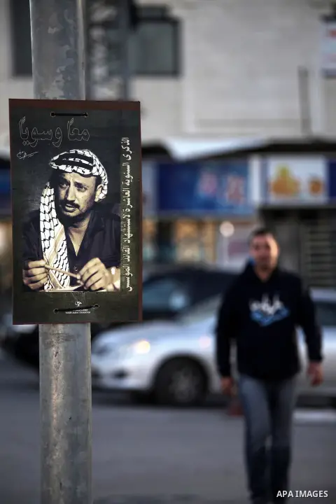 A Palestinian man walks past a picture of the late Palestinian leader Yasser Arafat on November 10, 2014, in the West Bank city of Ramallah, as Palestinians prepare to commemorate the 10th anniversary of the Arafat's dea...