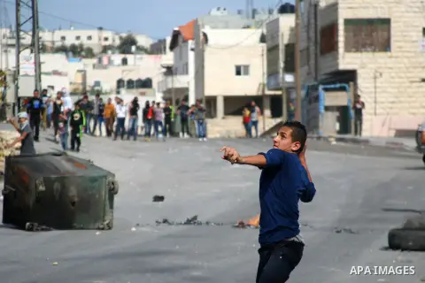 A Palestinian protester throws stones at Israeli soldiers during clashes on the outskirts of the West Bank city of Hebron on November 11, 2014. Clashes erupted as Israeli soldiers shot and killed 22 year-old Palestinian...