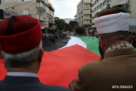 Palestinians carry a 100 meter long Palestinian flag during a rally on the 10th anniversary to commemorate the death of the late Palestinian leader Yasser Arafat and to mark the Palestinian declaration of independence, i...