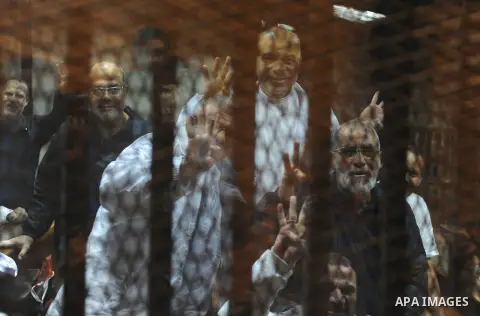 Muslim Brotherhood members sit inside the defendant's cage during their trial in cooperation cause in Cairo on Nov. 15, 2014. Morsi is being tried at a courtroom in the Police Academy in New Cairo along with 14 others on...