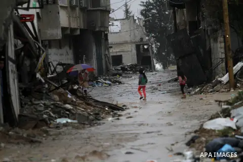 Palestinian children make their way to school in their neighbourhood which witnesses said was devastated by Israeli shelling during the most recent conflict between Israel and Hamas, on a rainy day in the east of Gaza Ci...