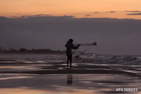 A Palestinian fisherman throws his net into the sea at the beach of Gaza City on Nov. 16, 2014. Photo by Yasser Qudih