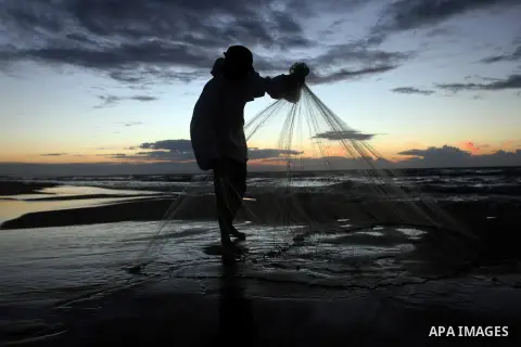 A Palestinian fisherman throws his net into the sea at the beach of Gaza City on Nov. 16, 2014. Photo by Yasser Qudih