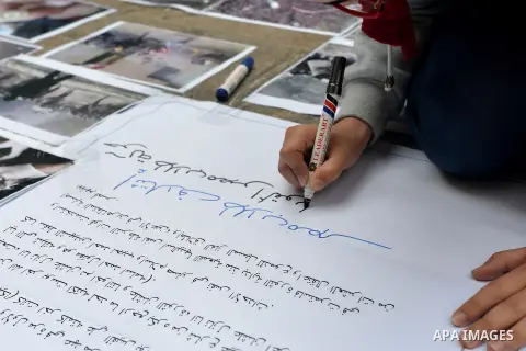 An Egyptian student writes placards during a street photo gallery organised by Misr Al-Qawia Party to commemorate the 3rd anniversary of deadly Mohamed Mahmoud clashes, at Cairo University on November 19, 2014. A number...