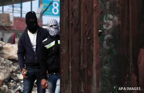 Palestinian protesters look on during clashes with Israeli security forces following a protest against Israeli restrictions to Al-Aqsa Mosque in Jerusalem, at the Qalandia checkpoint near the West Bank city of Ramallah,...