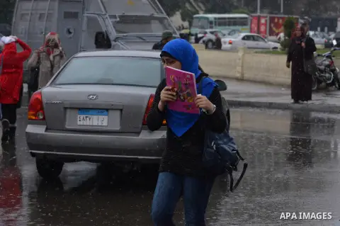 Egyptian students walk in the rain during a sudden downpour, at Cairo University, in Cairo, Egypt, on November. 24, 2014. Photo by Amr Sayed
