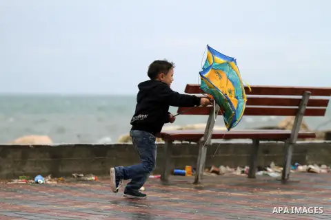 A Palestinian boy holds an umbrella during a rainy day, on the beach in Gaza city November 24, 2014. Photo by Yasser Qudih