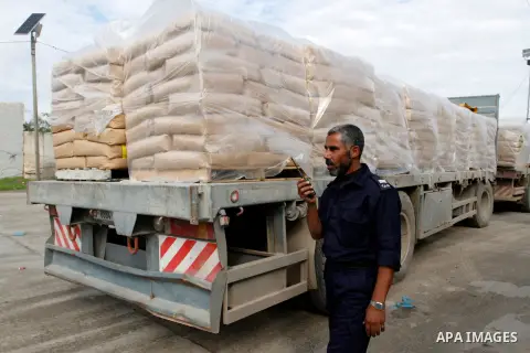 A Palestinian policeman walks past trucks loaded with cement that entered the Gaza Strip from Israel through the Kerem Shalom crossing in Rafah in the southern Gaza Strip on November 25, 2014. Twenty-eight trucks of ceme...