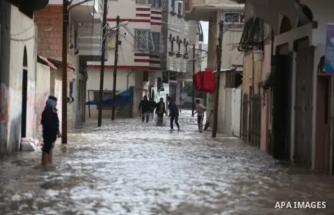 Palestinians make their way through a flooded street during heavy rains in Gaza City on November 27, 2014 as a fierce winter storm which has been battering the region for the past four days. Photo by Ashraf Amra