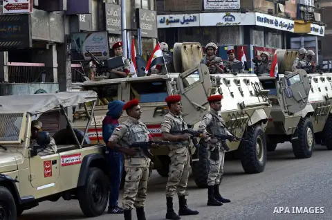 Egyptian security forces stand guard in front of armored vehicles in Cairo, Egypt, Friday, Nov. 28, 2014. Two senior Egyptian army officers were killed early Friday morning as security forces arrested more than 100 Islam...