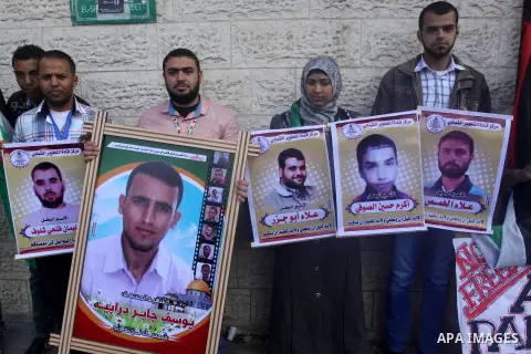 Palestinians hold posters as they take part a protest demanding the release of their relatives prisoners held in Israeli jails, in front of the Red Cross office in Gaza City, on Dec. 01, 2014. Photo by Mohammed Asad
