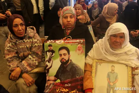 Palestinians hold posters as they take part a protest demanding the release of their relatives prisoners held in Israeli jails, in front of the Red Cross office in Gaza City, on Dec. 01, 2014. Photo by Mohammed Asad