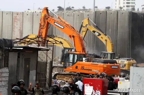 Construction vehicles under the supervision of Israeli forces destroy Palestinian owned shops that were built without a permit in the Shuafat refugee camp in east Jerusalem, on December 3, 2014. Palestinian homes built w...