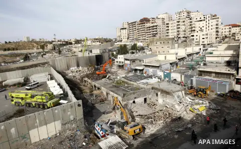 Construction vehicles under the supervision of Israeli forces destroy Palestinian owned shops that were built without a permit in the Shuafat refugee camp in east Jerusalem, on December 3, 2014. Palestinian homes built w...