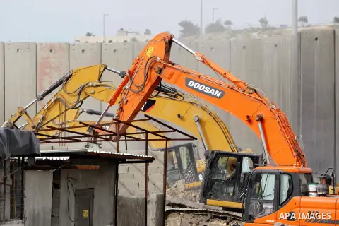 Construction vehicles under the supervision of Israeli forces destroy Palestinian owned shops that were built without a permit in the Shuafat refugee camp in east Jerusalem, on December 3, 2014. Palestinian homes built w...