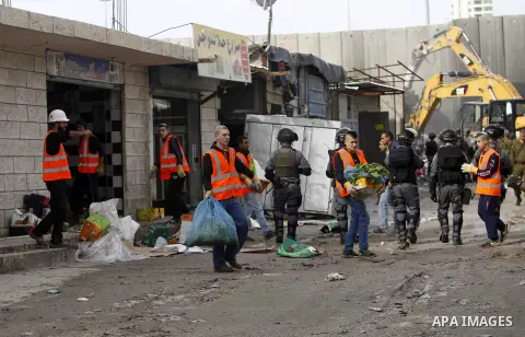 Israeli security forces stand guard while construction vehicles destroy Palestinian owned shops that were built without a permit in the Shuafat refugee camp in east Jerusalem, on December 3, 2014. Palestinian homes built...