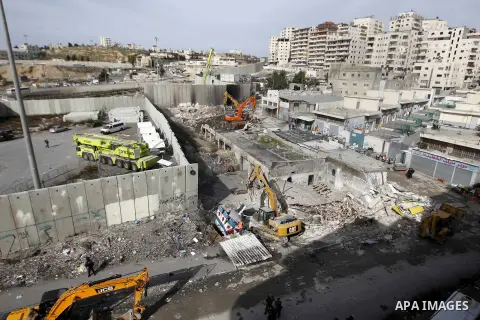 Construction vehicles under the supervision of Israeli forces destroy Palestinian owned shops that were built without a permit in the Shuafat refugee camp in east Jerusalem, on December 3, 2014. Palestinian homes built w...