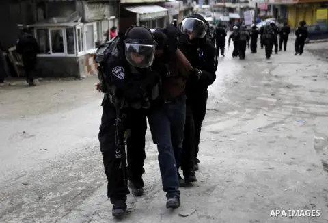 Israeli security forces detain a Palestinian man while construction vehicles destroy Palestinian owned shops that were built without a permit in the Shuafat refugee camp in east Jerusalem, on December 3, 2014. Palestinia...