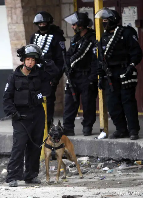 Israeli security forces stand guard while construction vehicles destroy Palestinian owned shops that were built without a permit in the Shuafat refugee camp in east Jerusalem, on December 3, 2014. Palestinian homes built...