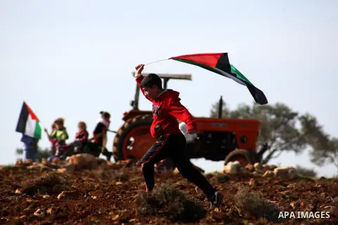 Palestinian children waving Palestinian flags play near a tractor at an agricultural land in Salem village, near the West Bank city of Nablus, December 5, 2014. Many groves are effectively off limits to Palestinians or t...