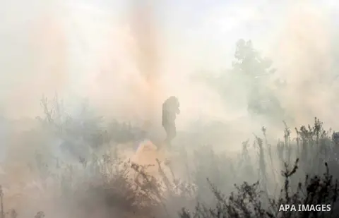 A Palestinian protester walks amid of a tear gas cloud fired by Israeli security forces during clashes following a demonstration against Israel's controversial barrier, in the outskirts of the village of Bilin, near the...