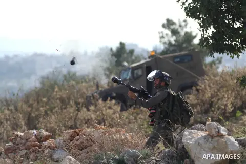 A member of Israeli security forces fires tear gas towards Palestinian protesters during clashes following a demonstration against Israel's controversial barrier, in the outskirts of the village of Bilin, near the West B...