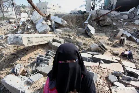 Palestinian female supporter of the Popular Front for the Liberation of Palestine (PFLP) sits next of damaged building during a protest against the delay in acquiring building material in front of the United Nations offi...