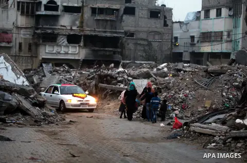 Palestinians walk past the rubbles of houses, which were destroyed during the recent Israeli offensive on Gaza Strip, in Shijaiyah neighborhood, east Gaza City, December 8, 2014. According to housing minister Mufeed al-H...