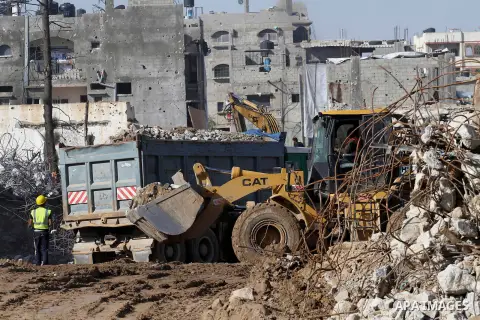 Palestinian workers use a bulldozer to remove the ruins of houses which were destroyed during the seven-week Israeli offensive on Gaza Strip, in Shijaeya neighborhood, east of Gaza city, December 10, 2014. According to h...