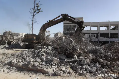 Palestinian workers use a bulldozer to remove the ruins of houses which were destroyed during the seven-week Israeli offensive on Gaza Strip, in Shijaeya neighborhood, east of Gaza city, December 10, 2014. According to h...
