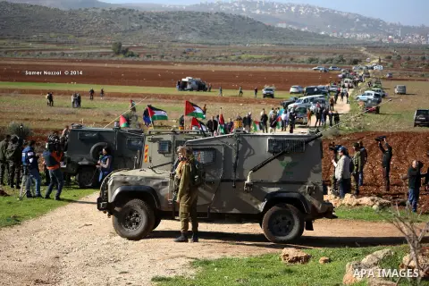 Israeli soldiers stand guard as Palestinians take part in a demonstration intended to plant 300 olive trees in the village of Turmus Aya near Ramallah, in the Isareli-occupied West Bank, on December 10, 2014. Ziad Abu Ei...