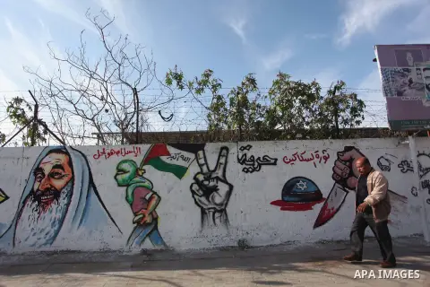 A Palestinian man walks past a mural marking the 27th anniversary of the Islamist movement's of Hamas founding at Nuseirat in the central of Gaza strip on December 11, 2014. Photo by Ashraf Amra