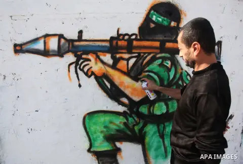 A Palestinian artist paints a mural on a wall marking the 27th anniversary of the Islamist movement's of Hamas founding at Nuseirat in the central of Gaza strip on December 11, 2014. Photo by Ashraf Amra