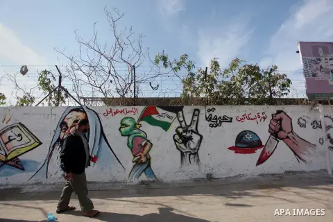 A Palestinian man walks past a mural marking the 27th anniversary of the Islamist movement's of Hamas founding at Nuseirat in the central of Gaza strip on December 11, 2014. Photo by Ashraf Amra