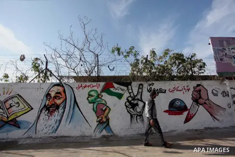 A Palestinian man walks past a mural marking the 27th anniversary of the Islamist movement's of Hamas founding at Nuseirat in the central of Gaza strip on December 11, 2014. Photo by Ashraf Amra