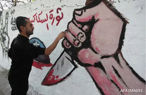 A Palestinian artist paints a mural on a wall marking the 27th anniversary of the Islamist movement's of Hamas founding at Nuseirat in the central of Gaza strip on December 11, 2014. Photo by Ashraf Amra