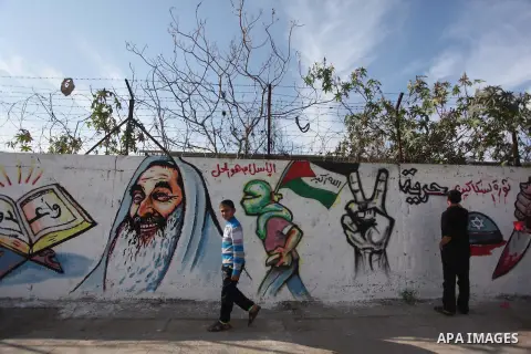 A Palestinian artist paints a mural on a wall marking the 27th anniversary of the Islamist movement's of Hamas founding at Nuseirat in the central of Gaza strip on December 11, 2014. Photo by Ashraf Amra