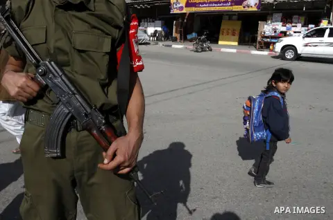 A Palestinian school boy looks on as members Palestinian security forces take part in a rally in solidarity with al-Aqsa mosque in Jerusalem, in Rafah in the southern Gaza Strip, December 11, 2014. Photo by Abed Rahim Kh...
