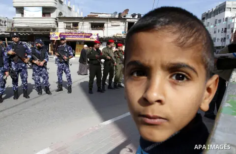 A Palestinian boy looks on as members Palestinian security forces take part in a rally in solidarity with al-Aqsa mosque in Jerusalem, in Rafah in the southern Gaza Strip, December 11, 2014. Photo by Abed Rahim Khatib